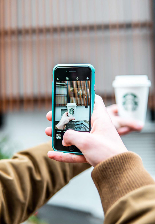 a person pointing at a Starbucks cup using a phone to signify unlokcing stories using Augmented Reality.